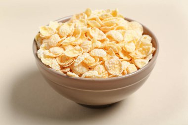 Bej arka planda lezzetli mısır gevrekleri olan kase, yakın plan.