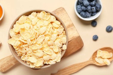 Bej arka planda lezzetli mısır gevreği ve yabanmersinli kompozisyon, yakın plan.