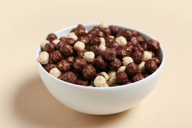 Bej arka planda çikolatalı mısır topları olan kase, yakın plan.