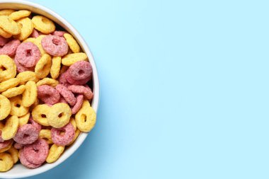 Mavi arka planda renk mısır gevreği halkaları olan kase, yakın plan.