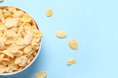 Mavi arka planda lezzetli mısır gevrekleri olan kase, yakın plan.