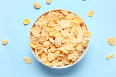 Mavi arka planda lezzetli mısır gevrekleri olan kase, yakın plan.