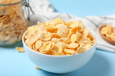 Mavi arka planda bir kase lezzetli mısır gevreği, yakın plan.