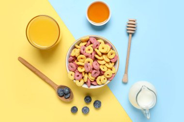 Bir bardak meyve suyu, bir kase lezzetli renk mısır gevreği halkaları ve arkaplanda bal ile kompozisyon