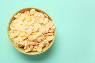 Turkuaz arka planda lezzetli mısır gevrekleri olan kase, yakın plan.