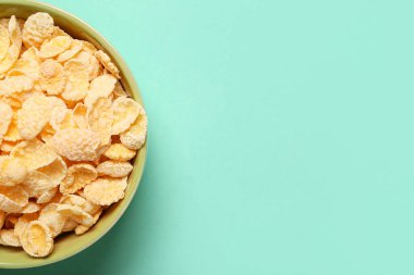 Turkuaz arka planda lezzetli mısır gevrekleri olan kase, yakın plan.