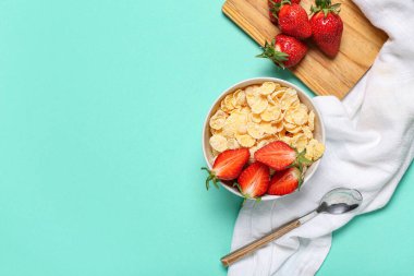 Turkuaz arka planda lezzetli mısır gevreği, çilek ve peçete kompozisyonu