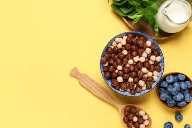 Lezzetli çikolatalı mısır topları, nane yaprakları ve böğürtlenli kompozisyon sarı arka planda