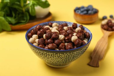 Sarı arka planda bir kase lezzetli mısır gevreği, yakın plan.