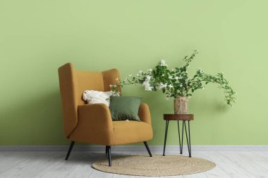 Oturma odasının içinde koltuk, masa ve vazo çiçekli yasemin çiçekleri.