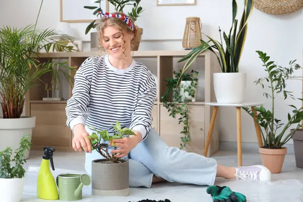 Evde yeşil bitkilerle ilgilenen genç bir kadın.