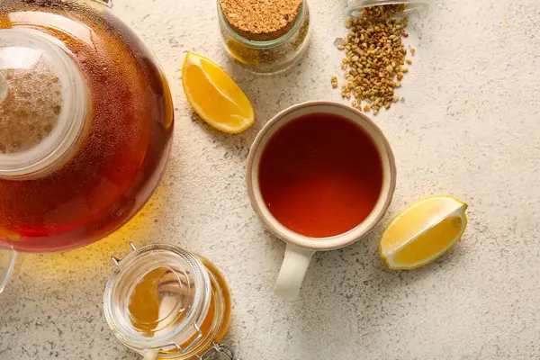 Bir fincan sıcak karabuğday çayı, beyaz arka planda limon ve bir kavanoz bal.