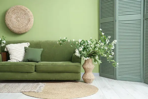 Oturma odasının içinde kanepe, katlanan perde ve çiçek açan vazo.