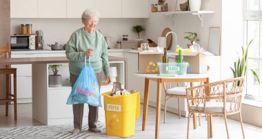 Mutfakta çöp torbası temizleyen yaşlı bir kadın.