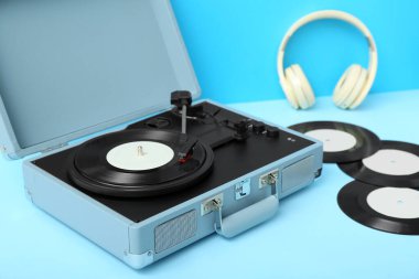 Plak çalar ve mavi masada vinil diskler ve kulaklıklar.