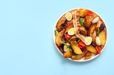 Yumurtalı, domatesli ve açık mavi arka planda domuz pastırmalı lezzetli patates salatası.