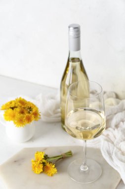 Beyaz masada bir şişe ve bir bardak karahindiba şarabı.