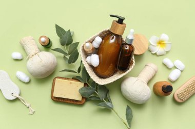 Kozmetik ürünleri, spa aksesuarları ve yeşil arka planda okaliptüs dalıyla kompozisyon