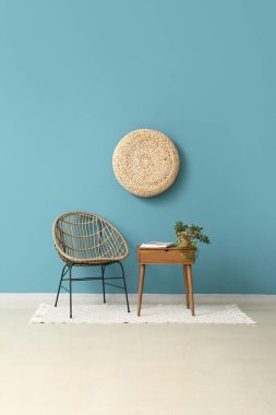 Konforlu koltuk ve sehpa, mavi duvarın yanında ev bitkisi ve dergiler var.