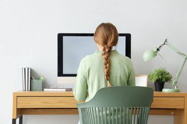 Ofisteki masada bilgisayarla çalışan genç bir kadın.