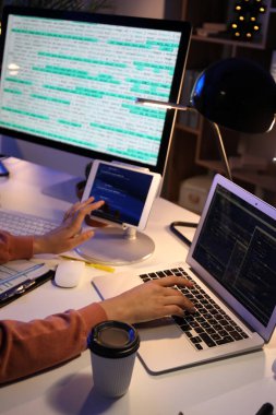 Geceleri ofiste cihazlarla çalışan kadın programcı, yakın plan
