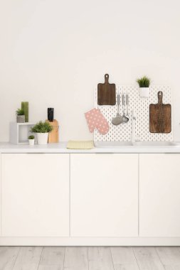 Kesme tahtaları, tahta, lavabo ve çatal bıçakları olan beyaz mutfak tezgahları.