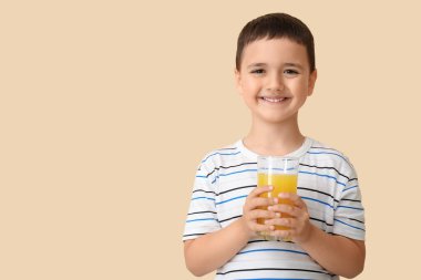 Bej arka planda bir bardak portakal suyu olan şirin bir çocuk.