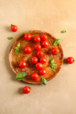 Taze kiraz domatesli ahşap masa ve kahverengi masada fesleğen.