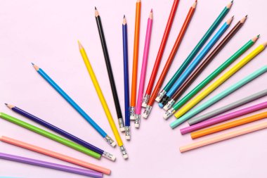 Açık pembe arka planda renkli kalemler grubu