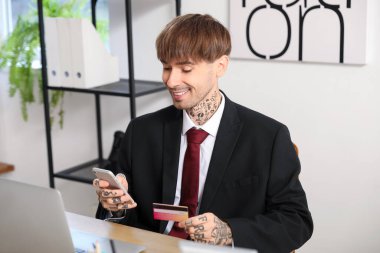 Ofiste cep telefonu kullanan genç bir işadamı.