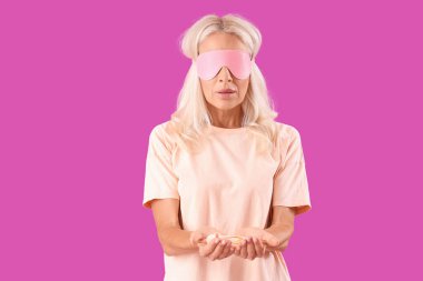 Mor arka planda vibratörü olan maskeli olgun bir kadın.