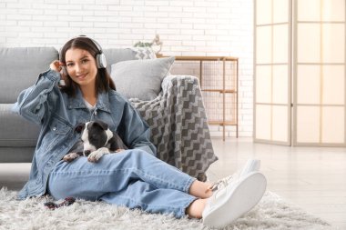 Kulaklıklı, evcil oyuncağı ve sevimli teriyer köpeği olan güzel bir kadın.