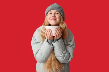 Kırmızı arka planda büyük bir fincan çayı olan güzel genç bir kadın.