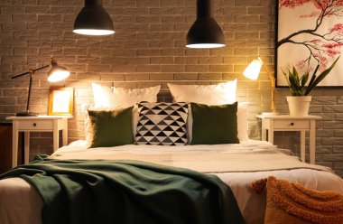 Rahat yatağın üzerinde battaniyeler ve gece lambaları olan modern yatak odasının içi.