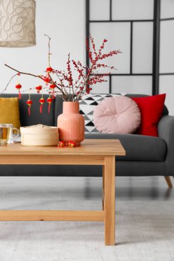 Oturma odasındaki masada ağaç dalları ve Çin sembolleri olan vazo. Yeni yıl kutlaması