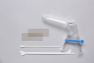 Gri arka planda pap smear test araçlarıyla jinekolojik spekulum