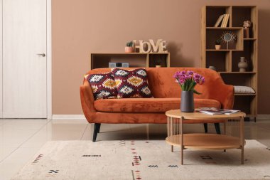 Kahverengi kanepesi ve kahve masasında güzel laleleri olan şık bir oturma odası.