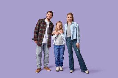 Mor arka planda şık kot elbiseli mutlu bir aile.