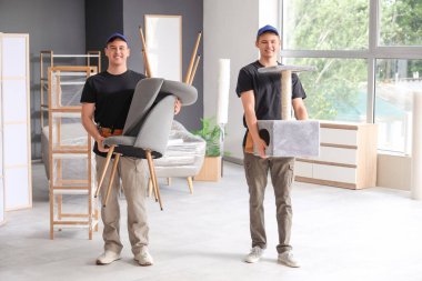 Şık bir odada sandalyeler taşıyan yükleyiciler