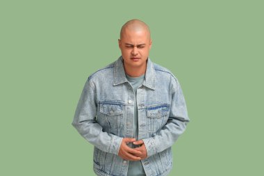 Yeşil arka planda apandisiti olan genç bir adam.