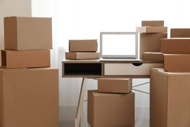 Boş dizüstü bilgisayar, odanın penceresinin yanındaki kutuların taşındığı masada.