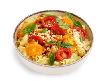 Beyaz arka planda domates ve fesleğenli bir kase lezzetli makarna.