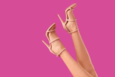 Mor arka planda bej renkli yüksek topuklu genç kadın bacakları