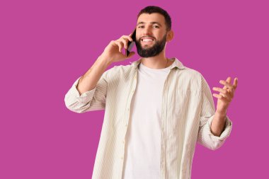 Mor arka planda cep telefonuyla konuşan yakışıklı genç adam.