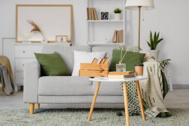 Oturma odasının içinde kitaplar olan rahat bir kanepe ve kahve masası.