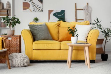 Konforlu kanepe, dergi ve çiçekli kahve masası oturma odasının iç tarafında.