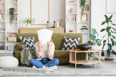 Oturma odasında halıda oturan not kağıtları ve sentezleyiciyle genç bir kadın.