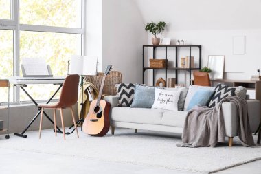 Kanepesi, sentezleyicisi ve gitarı olan bir oturma odası.