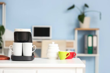 Ofisteki masada fincanlı kahve makinesi, yakın plan.