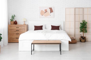 Büyük yataklı, katlanır ekran ve bitkilerle aydınlatma odasının içinde.